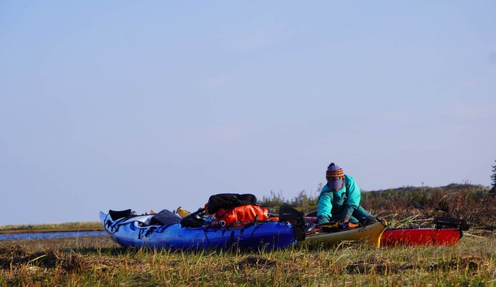 Kayakiste chargeant ses équipements dans son kayak de mer lors d'une expédition en Basse-Côte-Nord